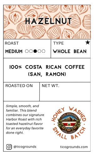 A flat product information card for Tico Grounds Hazelnut Whole Bean coffee. The card features a top section with a peach and white pattern of hazelnuts under the word 'HAZELNUT' in bold.