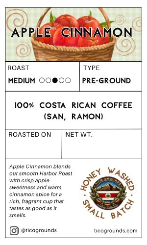 A coffee label card for 'Apple Cinnamon' roast coffee from ticogrounds, featuring a basket of red apples at the top, product details in the center, and a honey washed small batch seal at the bottom right.