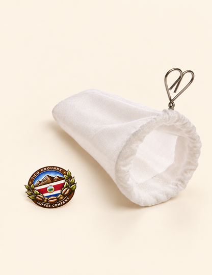 A white cotton drawstring pouch with a silver metal clip, shown on a light beige background next to a circular Guatemalan coffee company enamel pin.